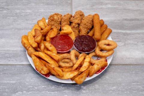Assiettes mixtes de la pizzeria de Michelangelo avec des bâtonnets de mozzarella, des ailes de poulet, des rondelles d'oignon et des frites ou des quartiers de pommes de terre